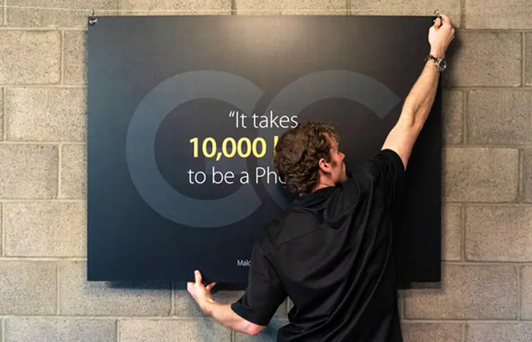 Man putting up branded poster on wall